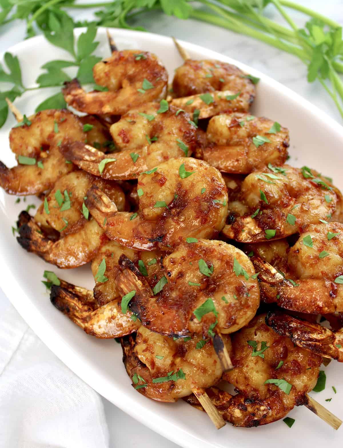 Air Fryer Asian Shrimp Skewers on white oval platter with chopped parsley