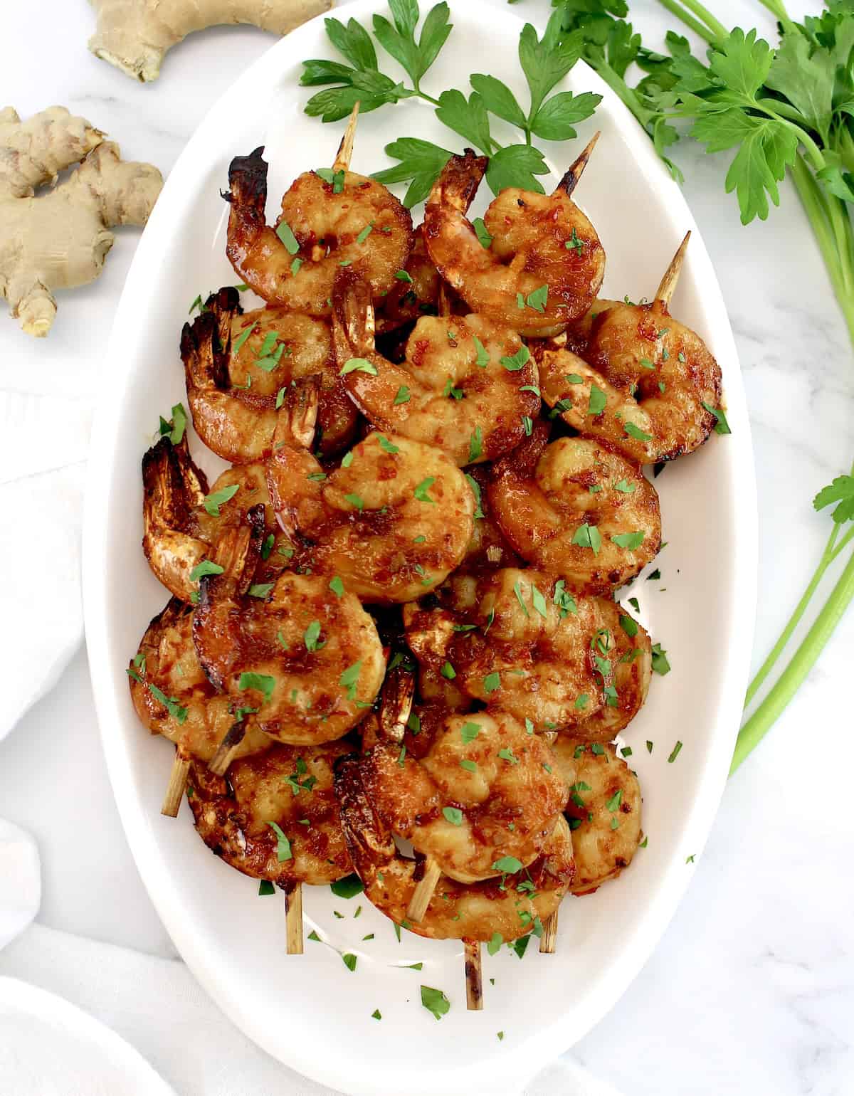 overhead view of Air Fryer Asian Shrimp Skewers on white oval platter with chopped parsley