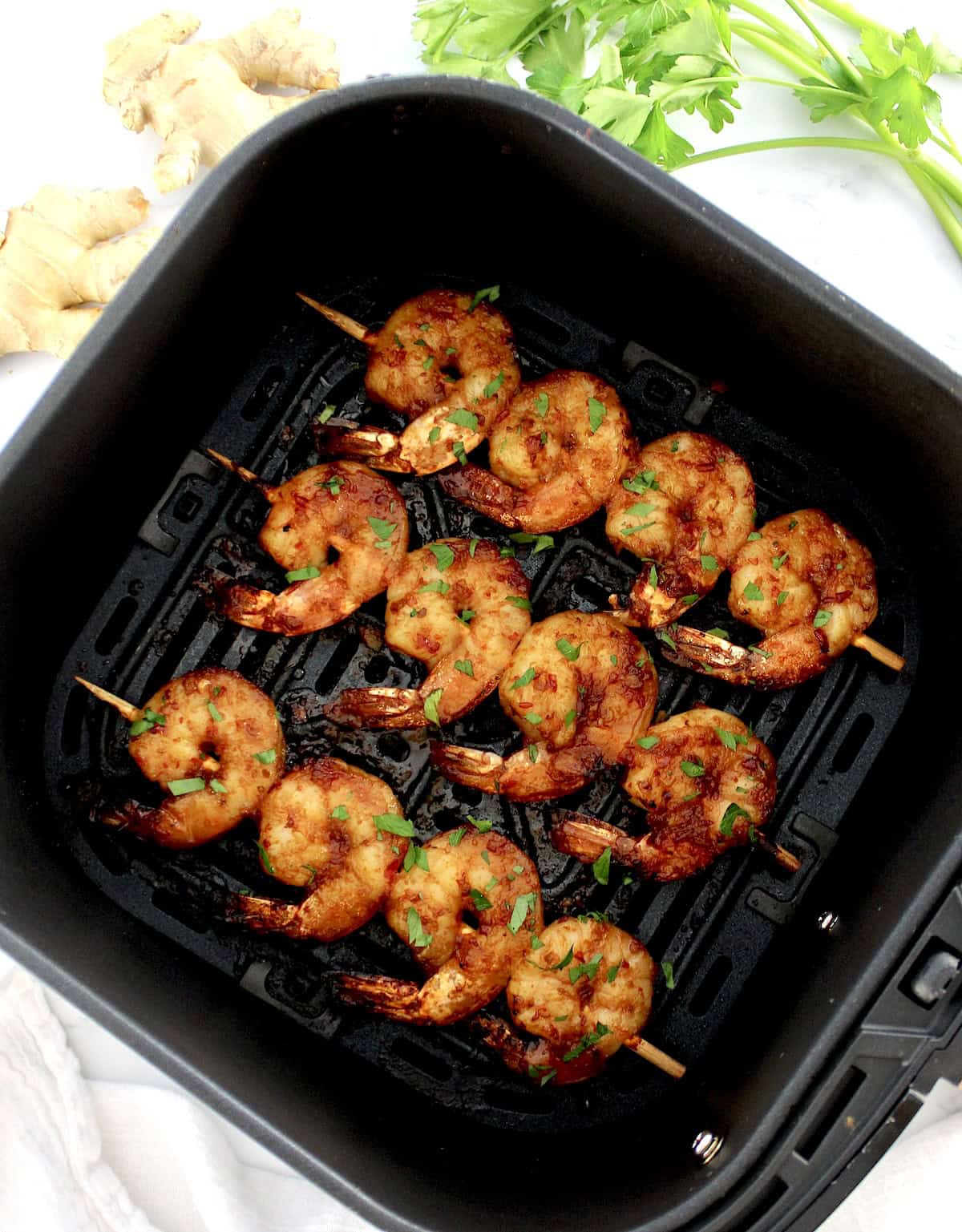 Air Fryer Asian Shrimp Skewers in air fryer basket with chopped parsley