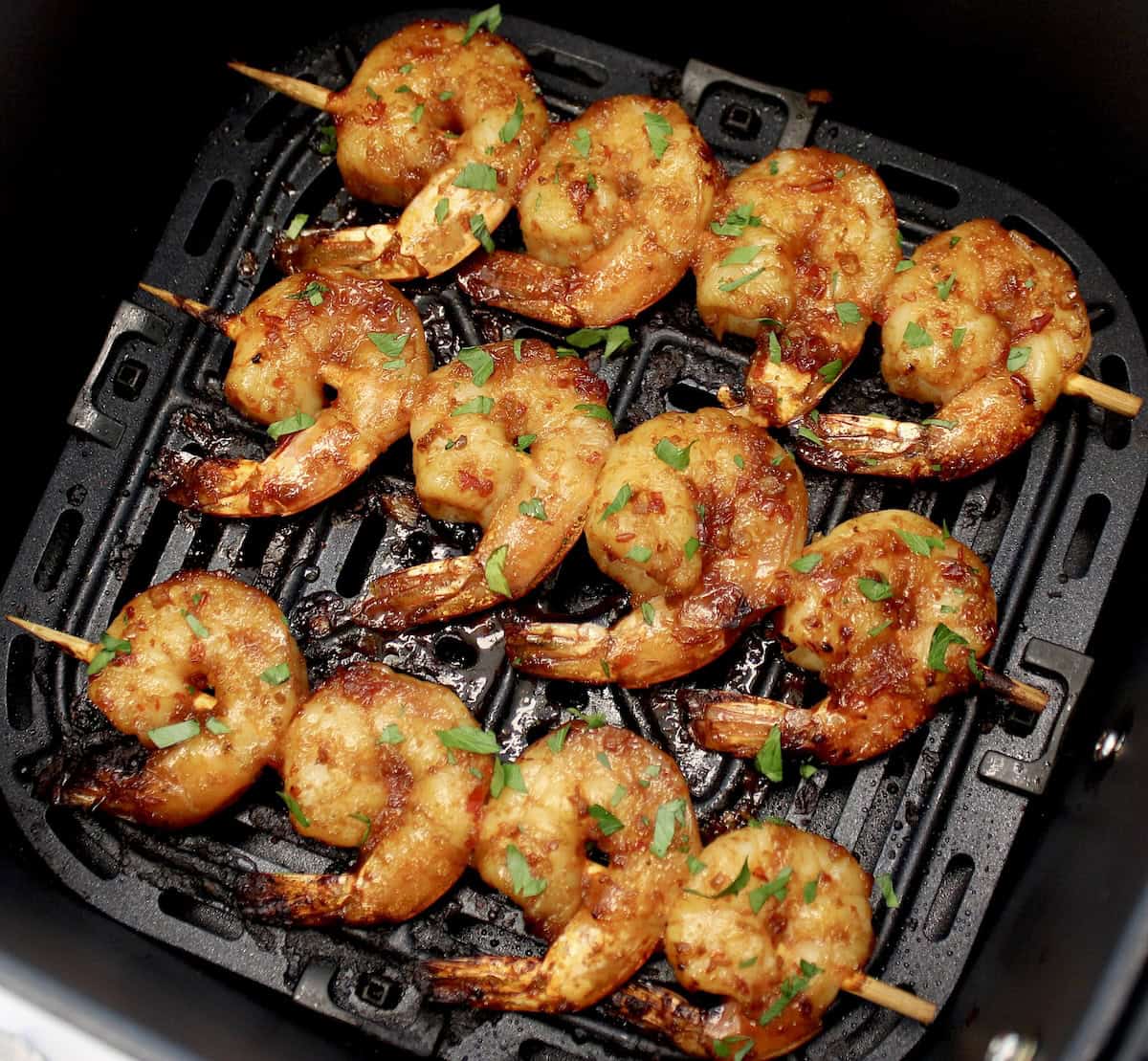 Air Fryer Asian Shrimp Skewers in air fryer basket with chopped parsley