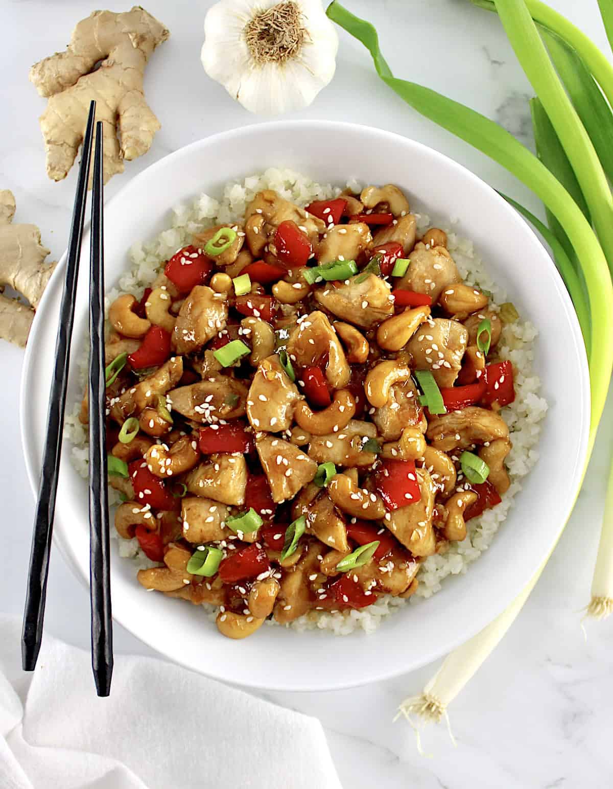 overhead view of Cashew Chicken over cauliflower rice with black chopsticks on side