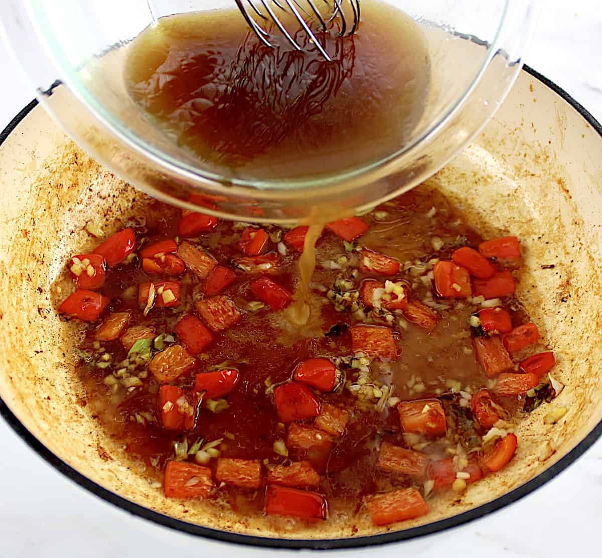 Cashew Chicken sauce being poured in skillet with red bell peppers and scallions