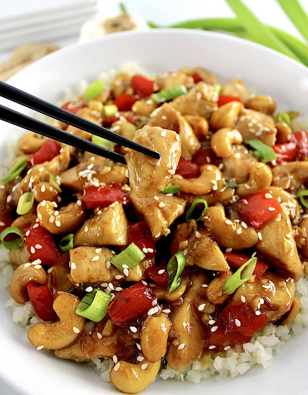 Cashew Chicken with chopsticks holding up piece of chicken