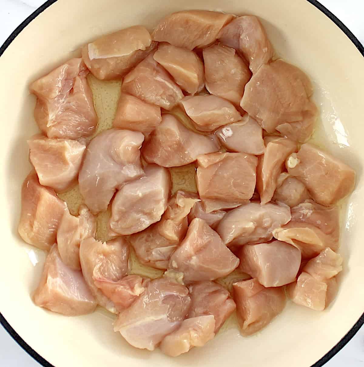 raw chunks of chicken in skillet