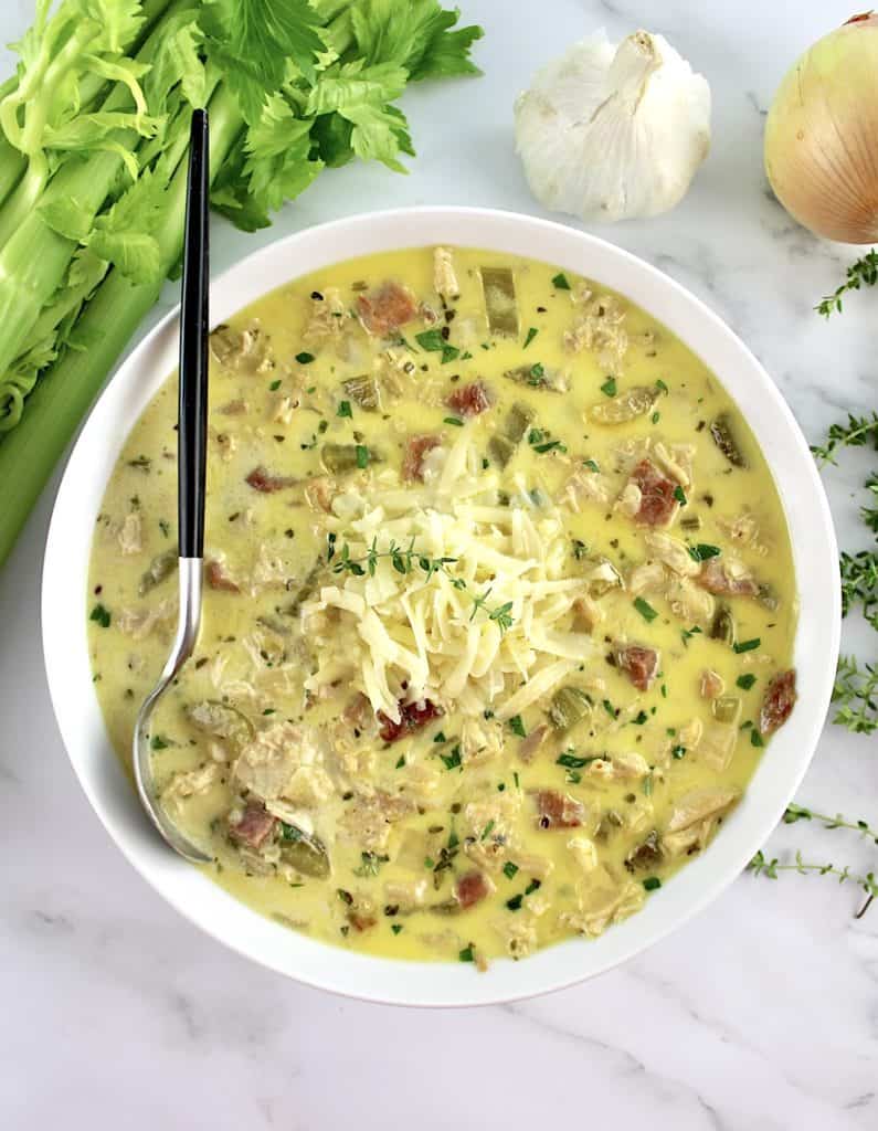 Chicken Cordon Bleu Soup in white bowl with spoon with black handle and veggies in back