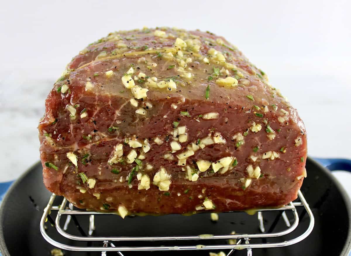 raw Roast Beef with garlic butter rub sitting on rack