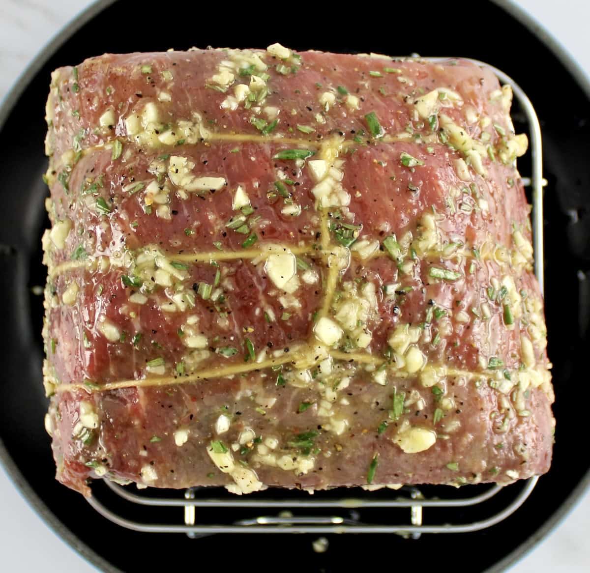 overhead view of raw roast beef with garlic herb rub