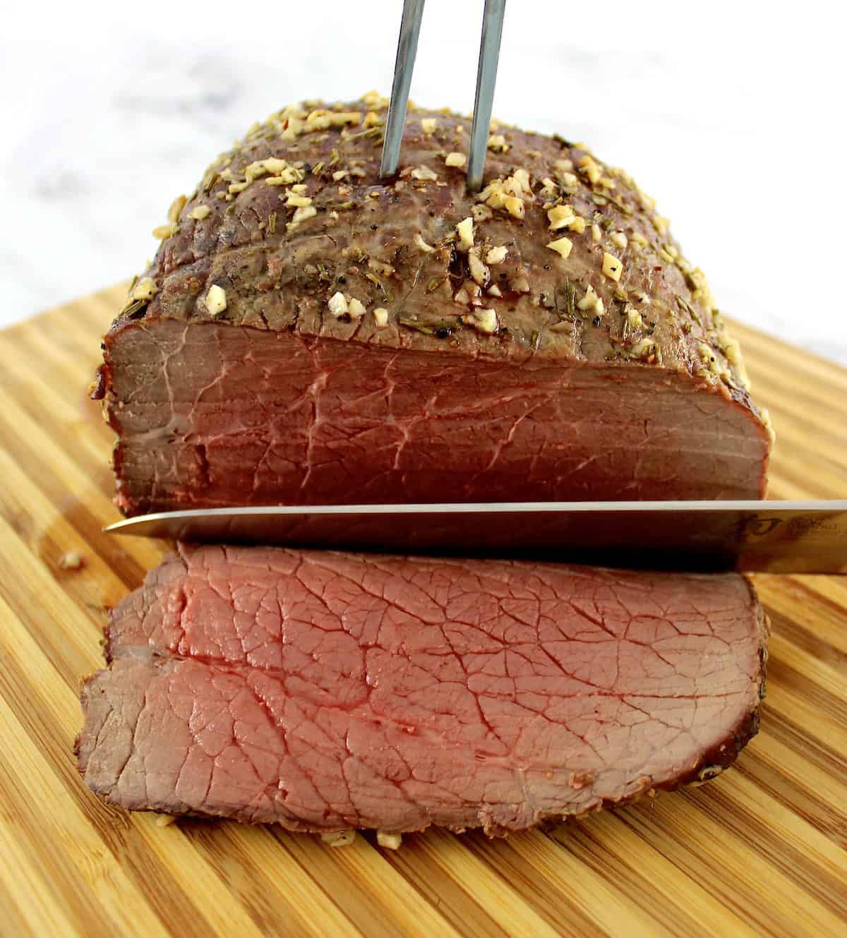 roast beef being sliced on cutting board