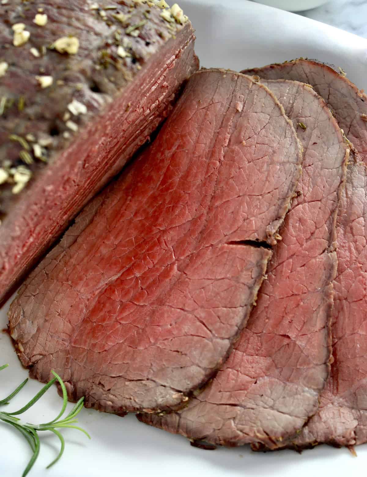 closeup of slices of roast beef on white plate