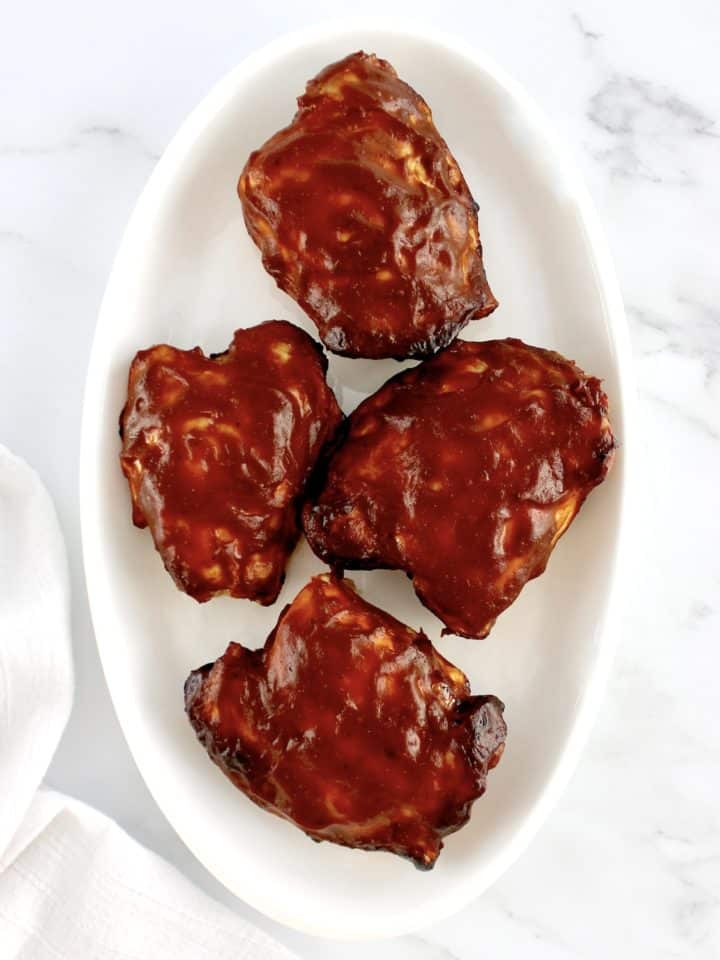 overhead view of 4 Air Fryer BBQ Chicken Thighs on white oval plate