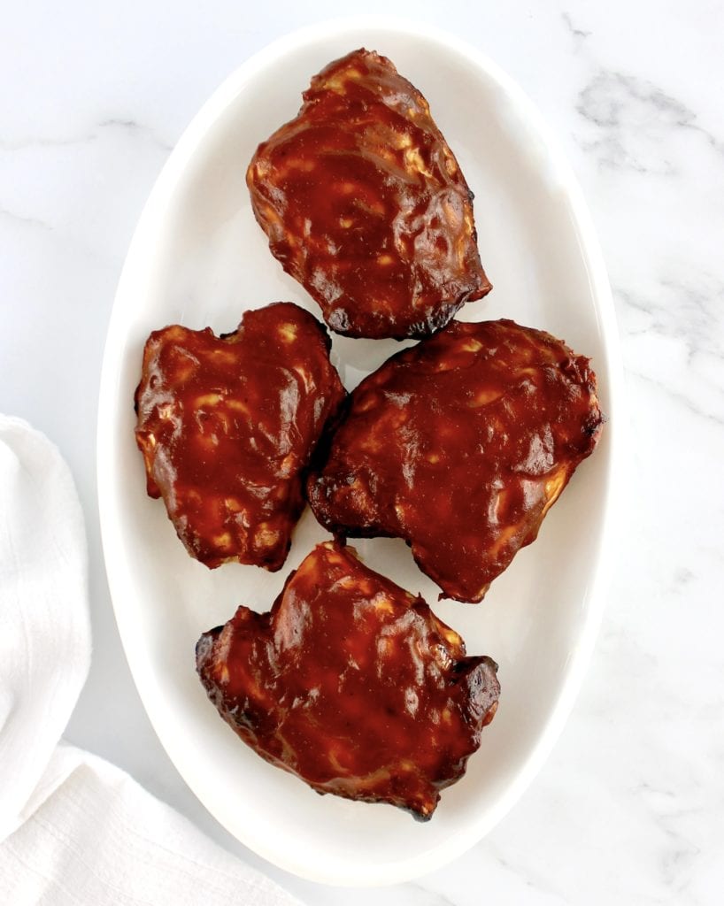 overhead view of 4 Air Fryer BBQ Chicken Thighs on white oval plate