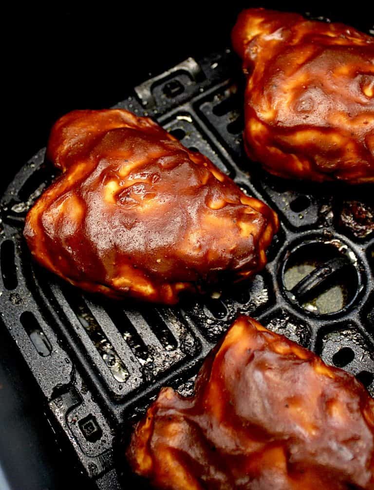 overhead closeup view of 3 Air Fryer BBQ Chicken Thighs in air fryer basket