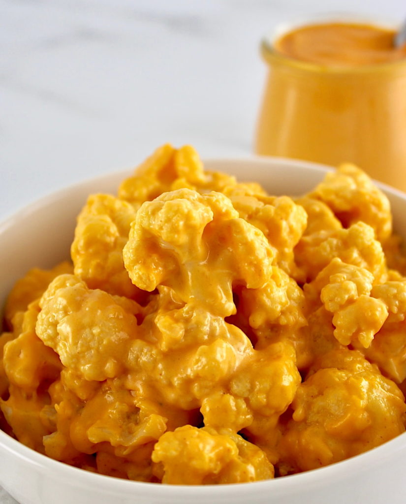 Buffalo Cauliflower Mac and Cheese in white bowl with sauce in back