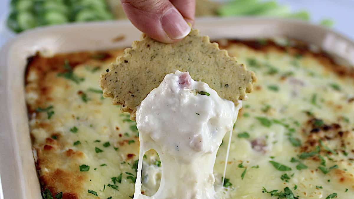 Chicken Cordon Bleu Dip being scooped up with cracker