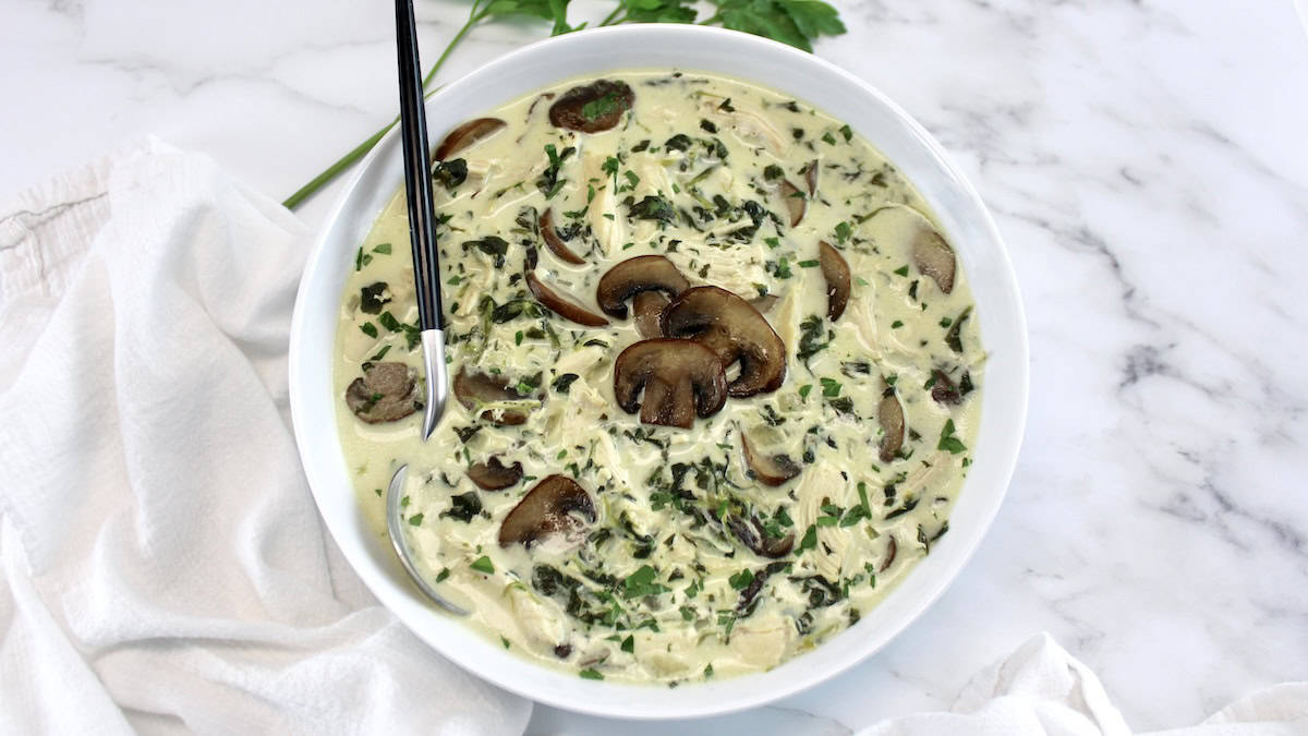 overhead view of Chicken Florentine Soup in white bowl with spoon