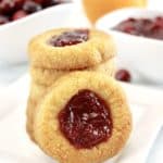 closeup of Cranberry Thumbprint Cookies stacked with one sideways on white plate