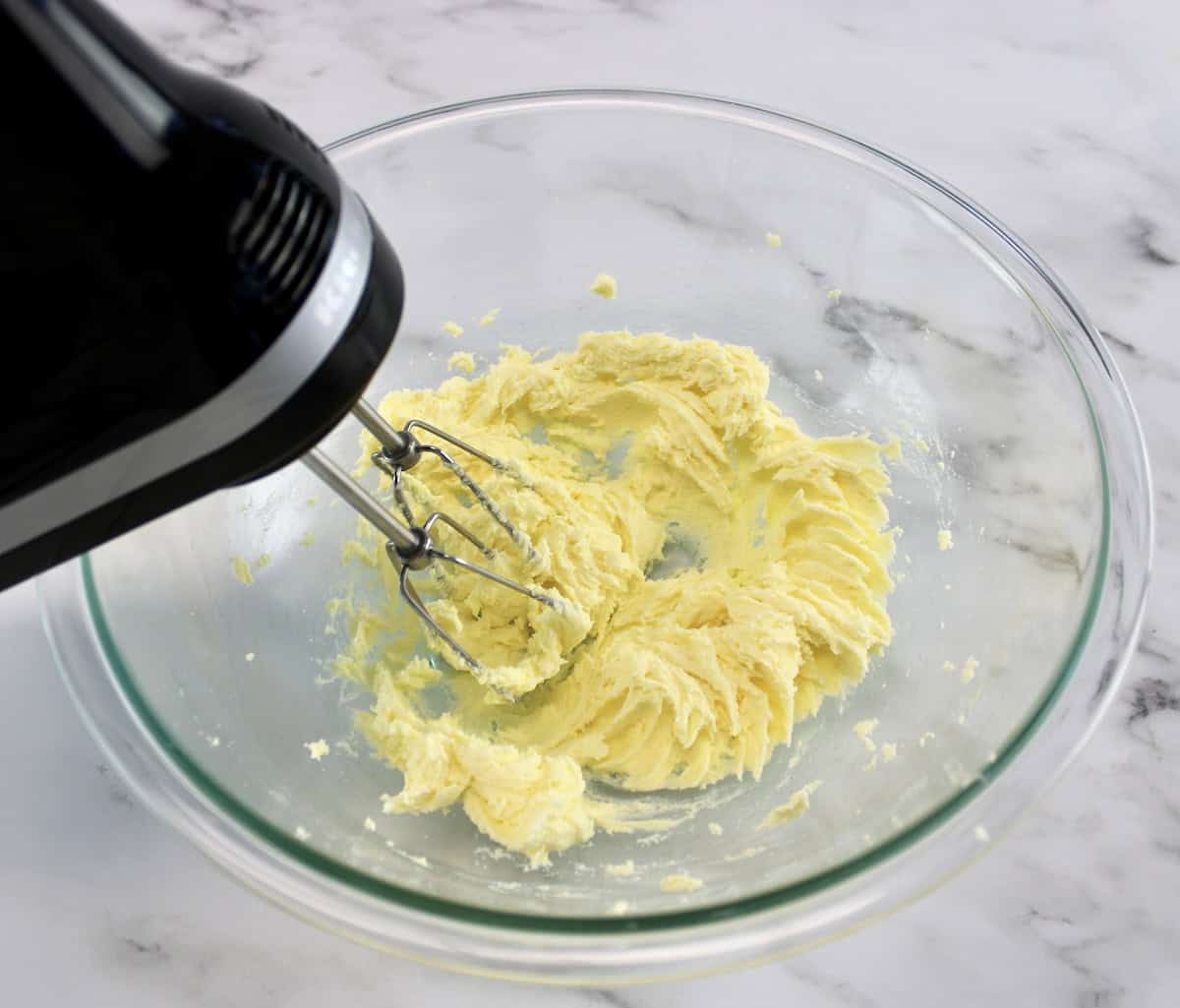 butter and sweetener being creamed together in glass bowl with hand mixer