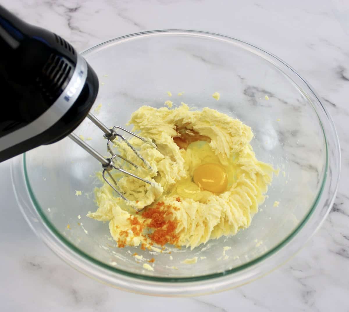 wet ingredients for Cranberry Thumbprint Cookies in glass bowl being whipped with hand mixer