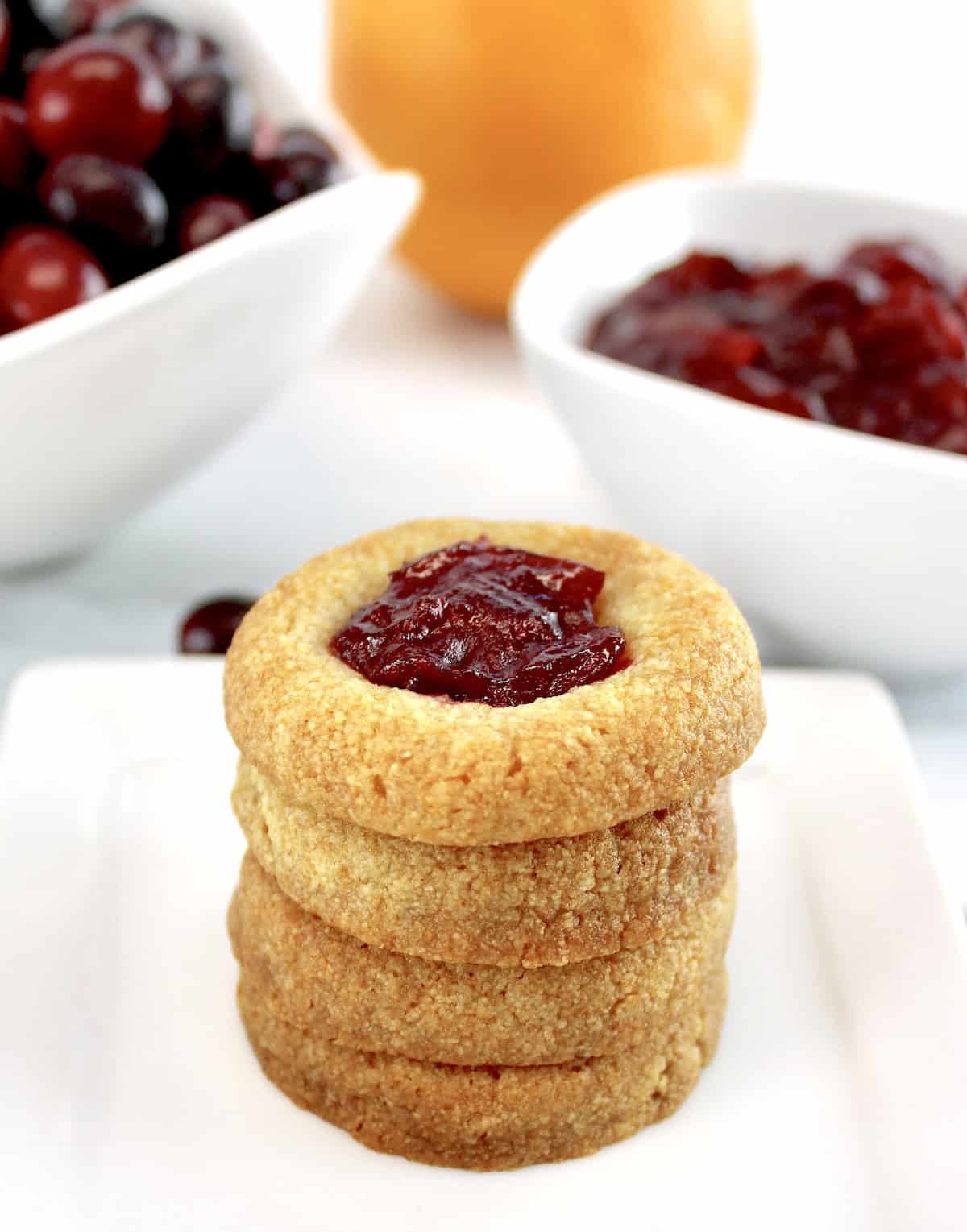 Cranberry Thumbprint Cookies stacked up on each other with cranberries in back