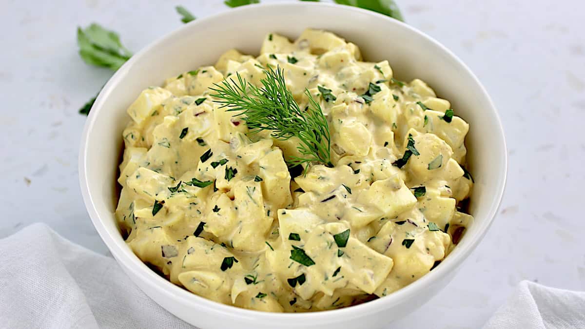 easy egg salad in white bowl with fresh dill on top