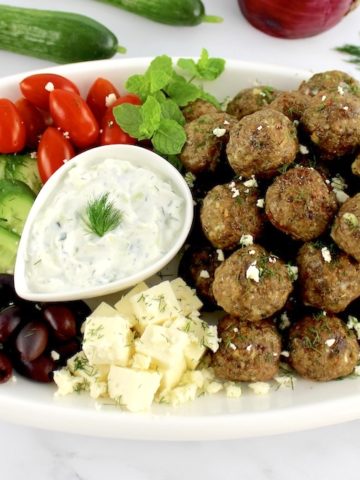 greek meatballs on platter with veggies and dipping sauce in center