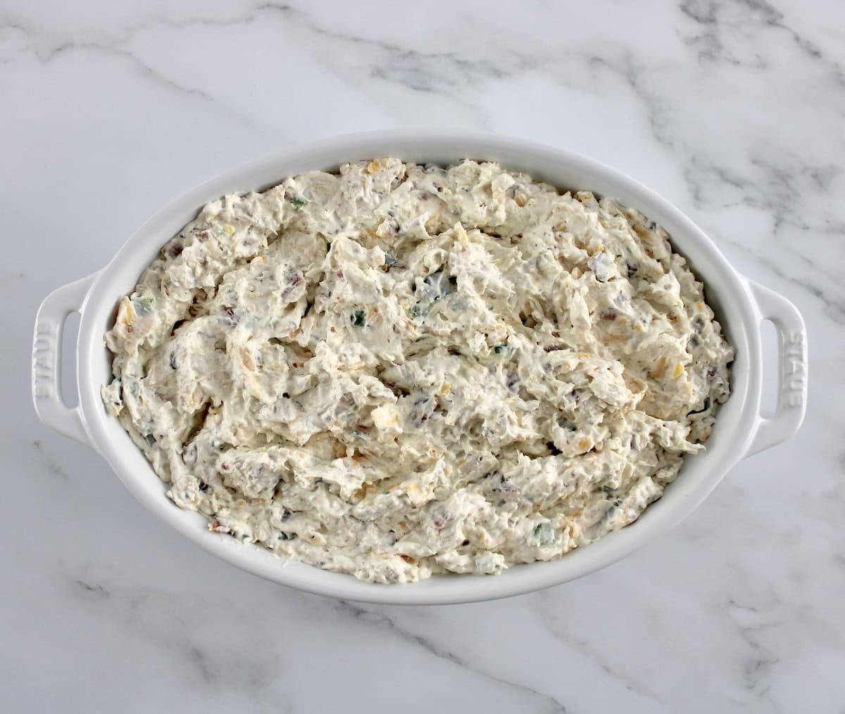 Jalapeño Popper Chicken Dip in white casserole dish unbaked