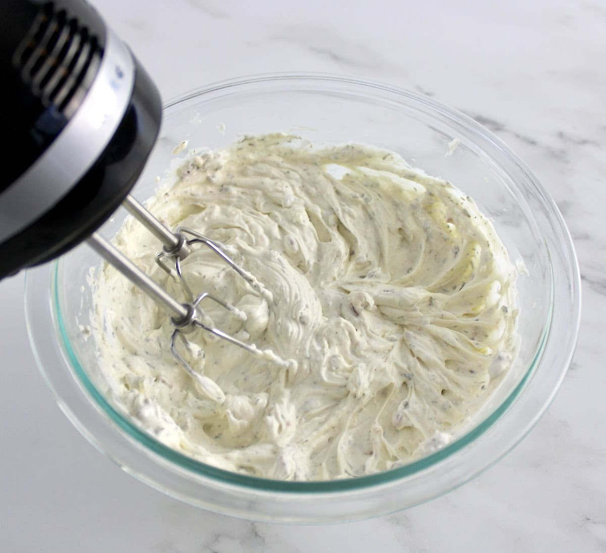 Jalapeño Popper Chicken Dip dressing in glass bowl being mixed with hand mixer