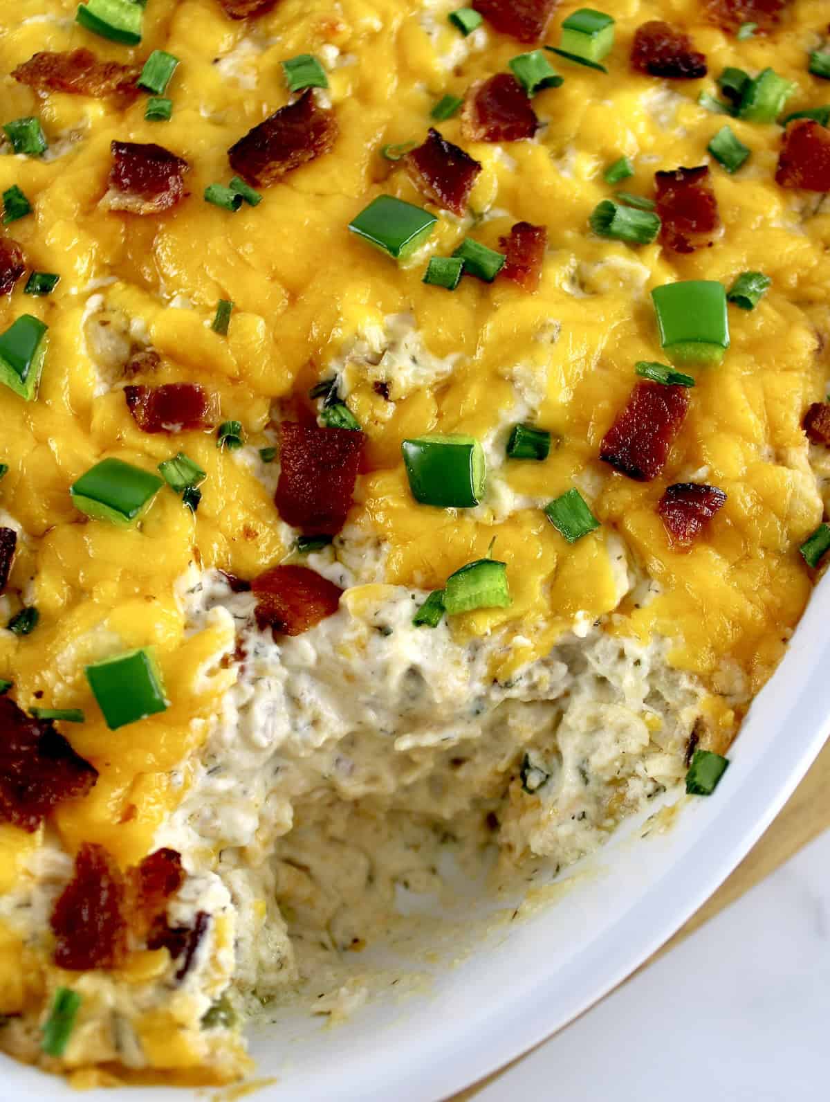 closeup of Jalapeño Popper Chicken Dip in white casserole with some missing