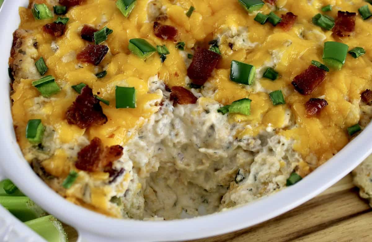 closeup of Jalapeño Popper Chicken Dip in white casserole with some missing