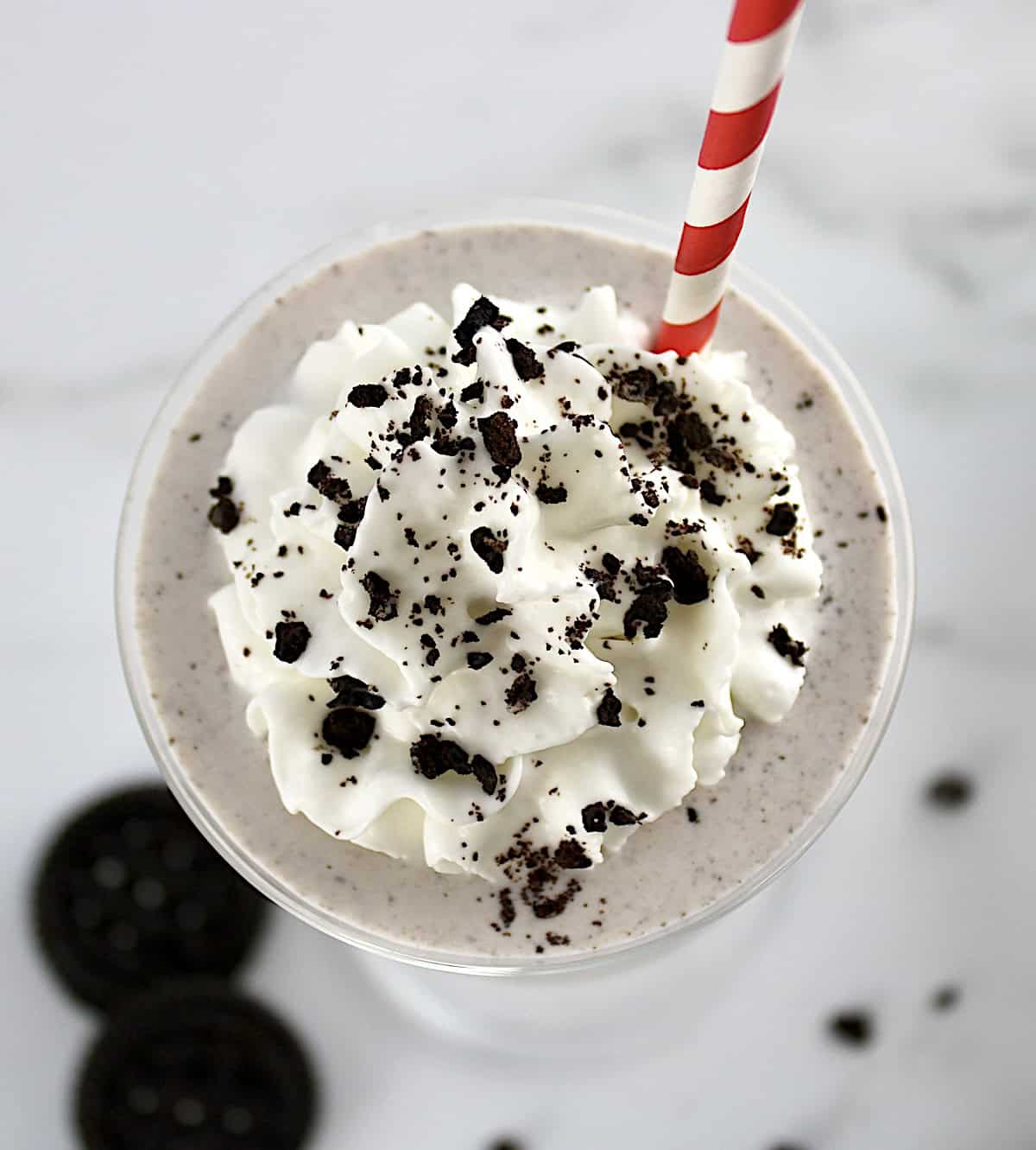 overhead view of Keto Cookies and Cream Milkshake with whip cream and crushed cookies on top with red straw