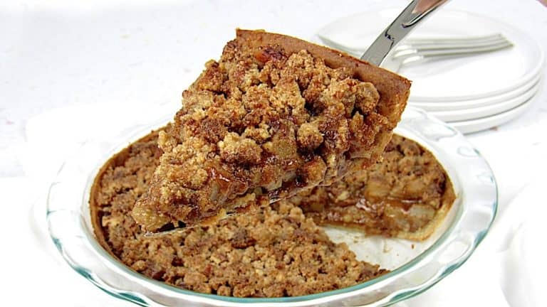 slice of dutch apple pie being held up over pie