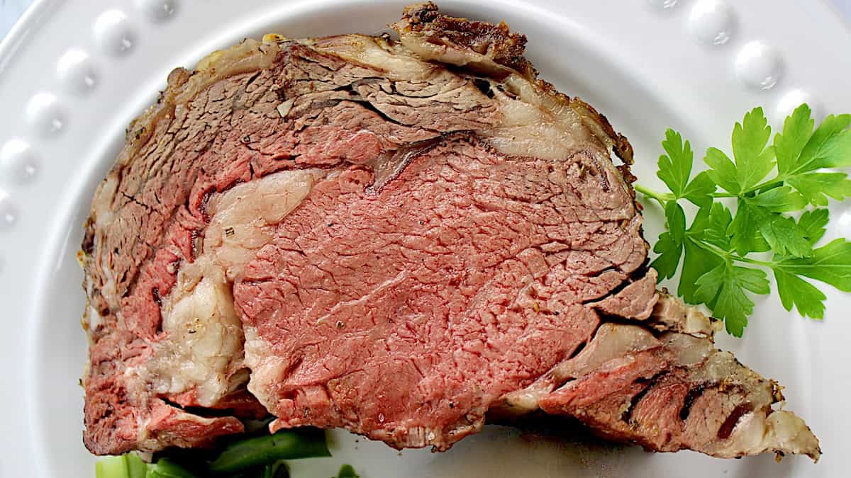 prime rib on white plate with fresh parsley garnish