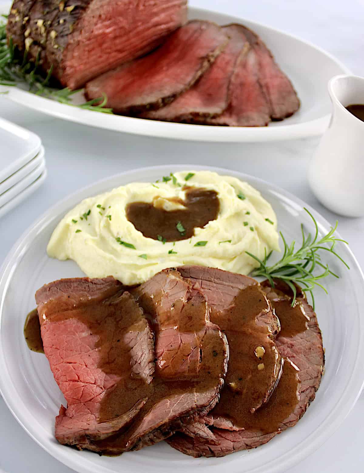 Roast Beef with Gravy on plate with mashed cauliflower and gravy with roast in back