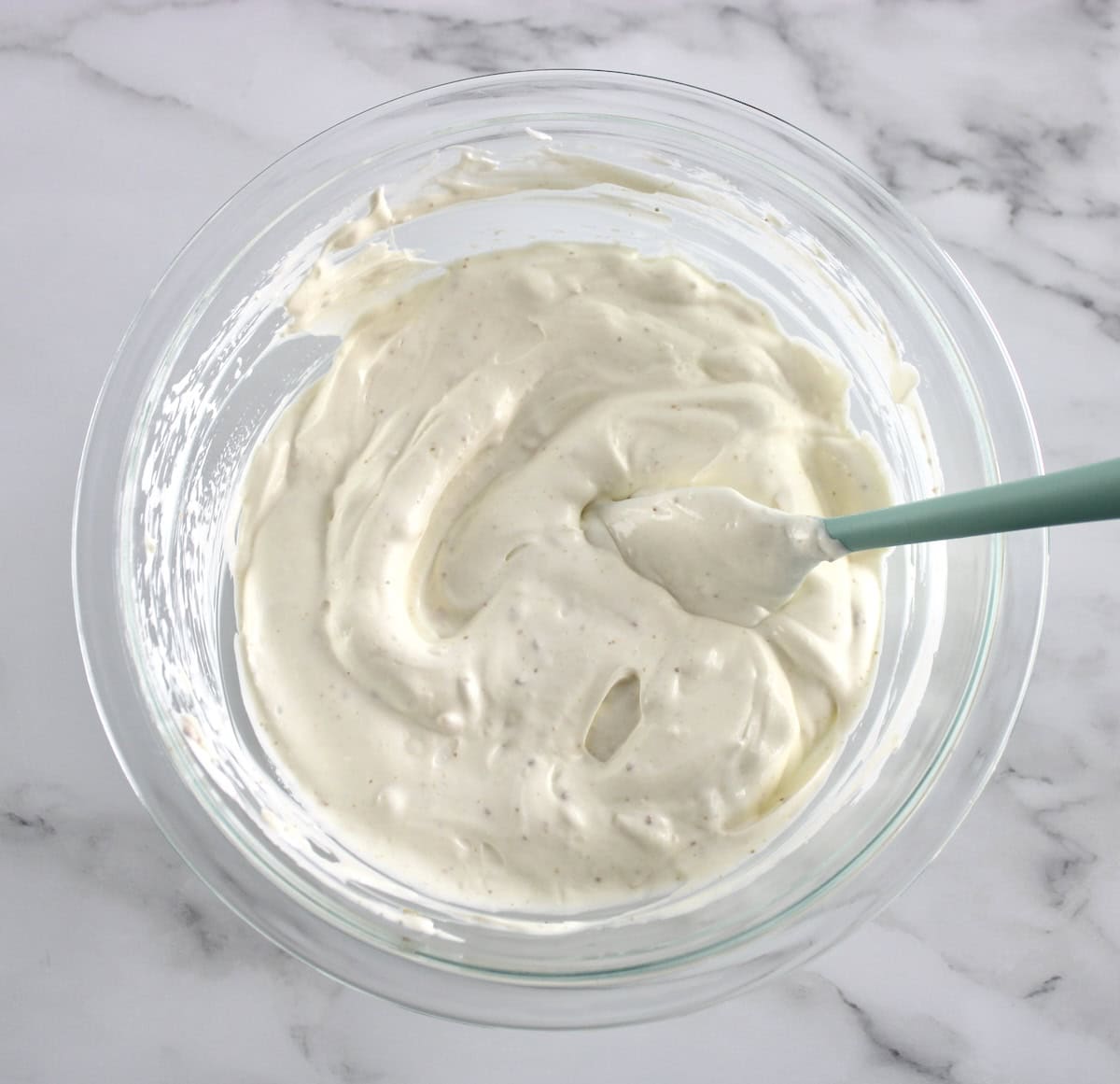 Spinach Dip ingredients without spinach in glass bowl with blue spoon