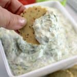 holding up cracker dipped in Spinach Dip