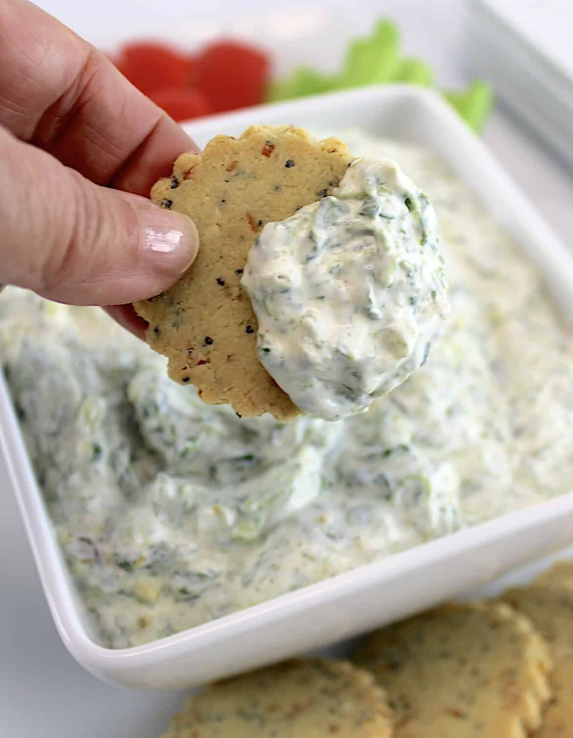 holding up cracker dipped in Spinach Dip