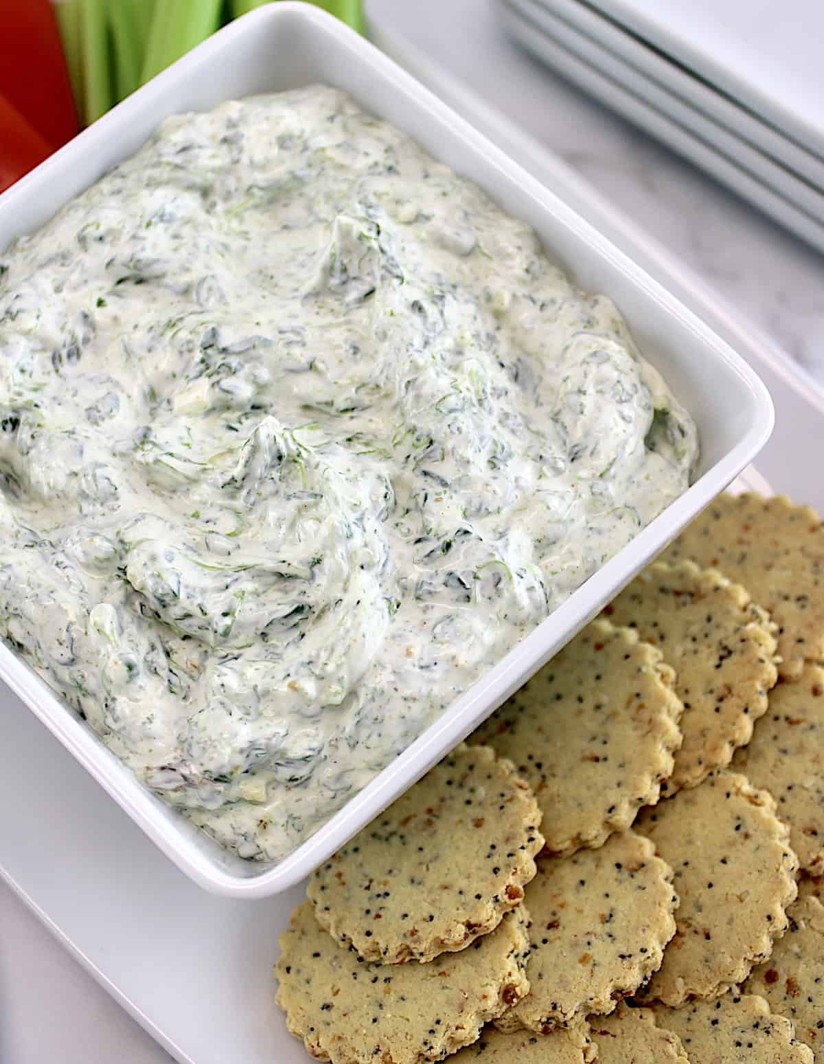 Spinach Dip in white square bowl with crackers on side