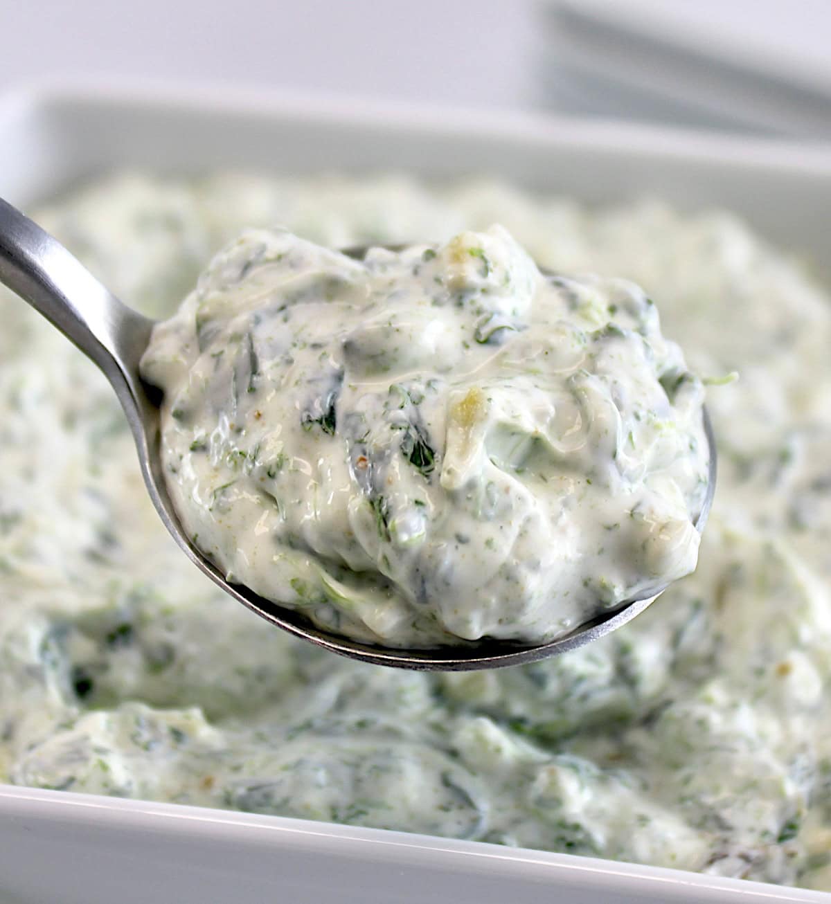 Spinach Dip in spoon held up over bowl