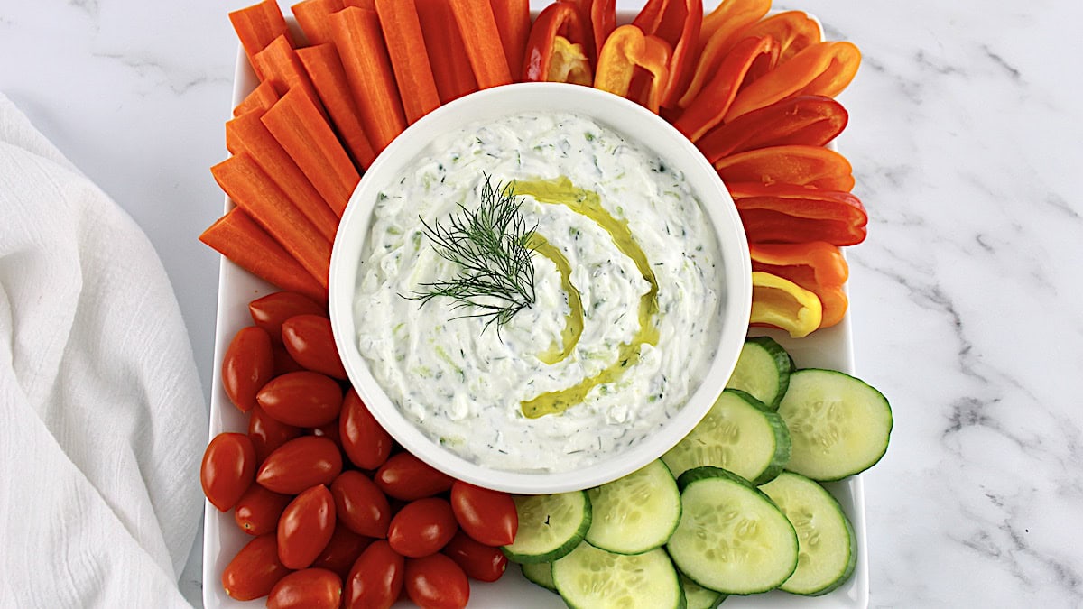 Tzatziki Sauce on white oval platter with raw veggies around