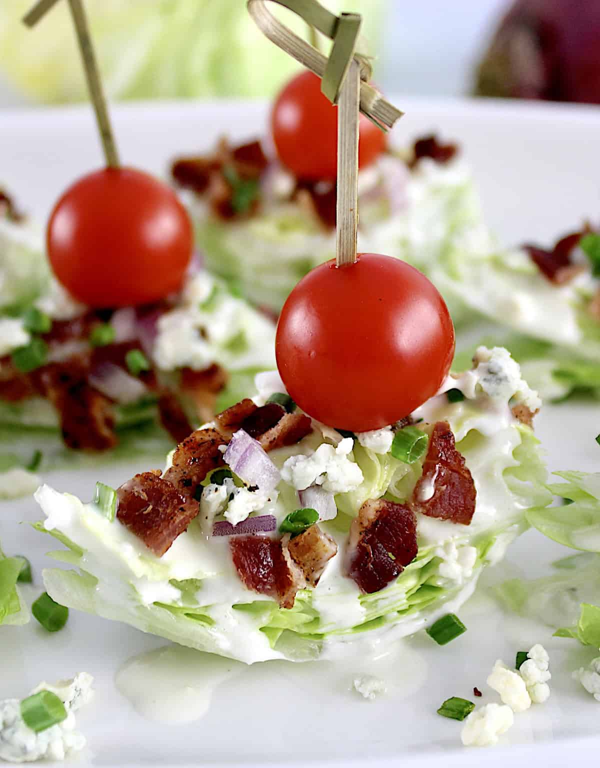 Wedge Salad Bites on white plate with cherry tomato through toothpick