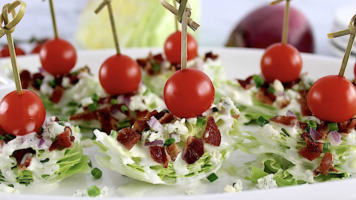 Wedge Salad Bites on white plate with cherry tomato through toothpick