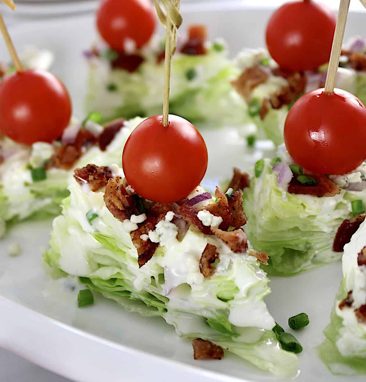 Wedge Salad Bites on white plate with cherry tomato through toothpick