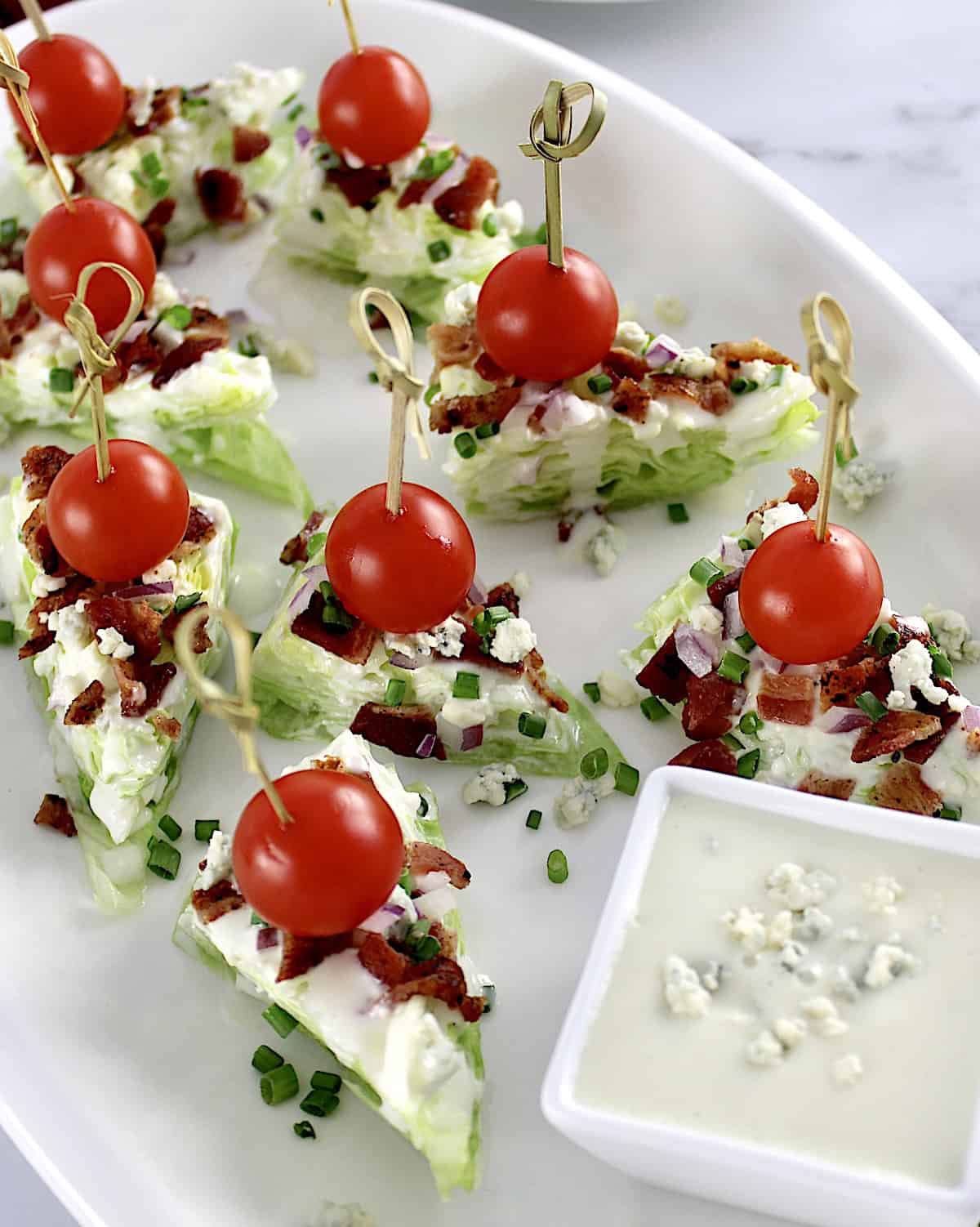 Wedge Salad Bites on white platter with blue cheese dressing in cup