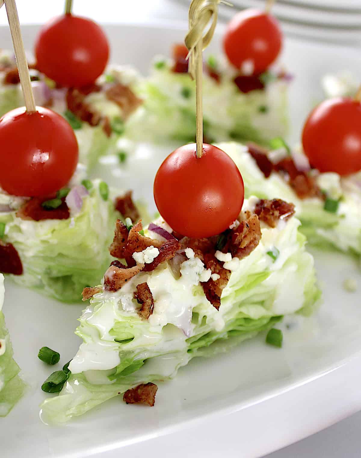 closeup of Wedge Salad Bites with bacon and cherry tomato through toothpick on top