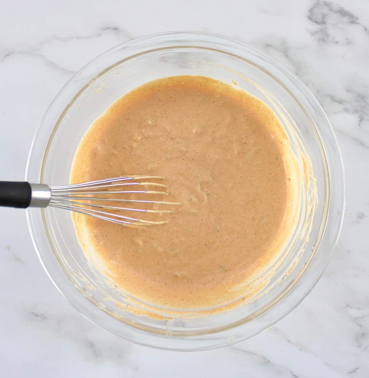 Bacon Cheeseburger Casserole sauce in glass bowl with whisk