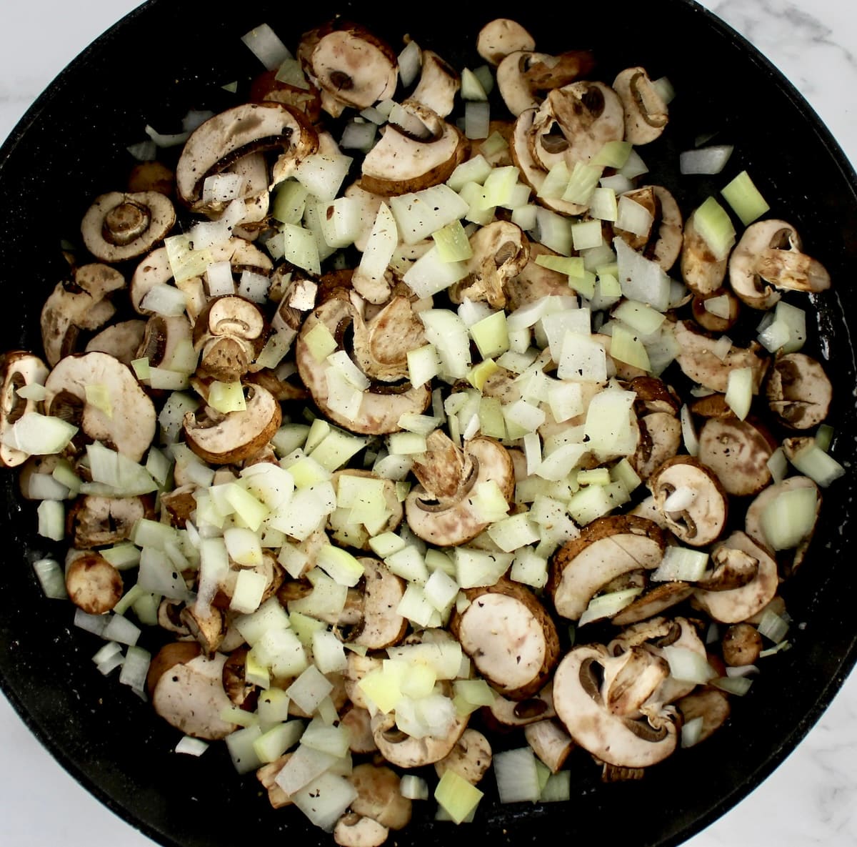 raw sliced mushrooms and onions in skillet