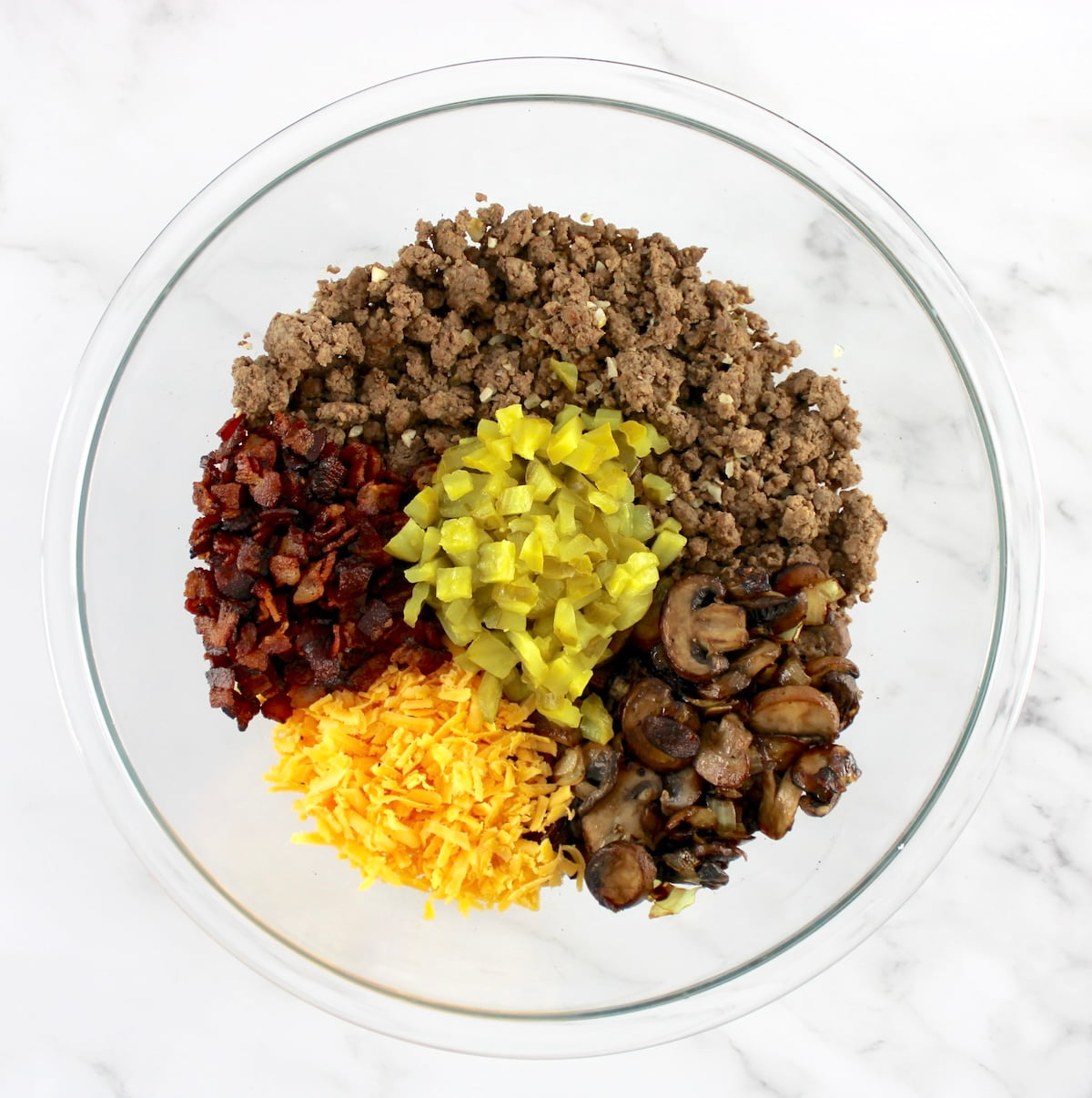 Bacon Cheeseburger Casserole ingredients in glass bowl in sections unmixed