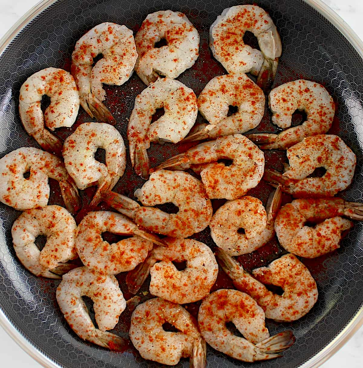 raw shrimp in skillet with salt, pepper and smoked paprika