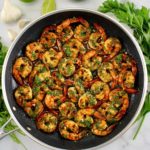 Chimichurri Shrimp in skillet with sauce and fresh herbs in back