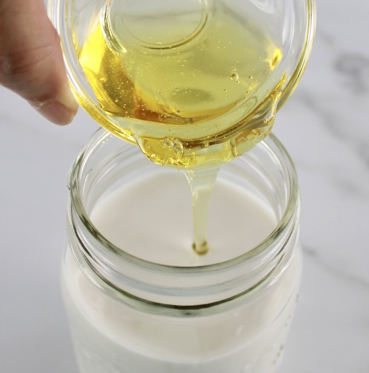 honey being poured into mason jar with coconut milk